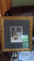 Full framed print showing ornate gold frame and matting with reflective glass and backing visible.