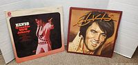 Photo showing two Elvis Presley record albums with visible cover artwork and some wear.