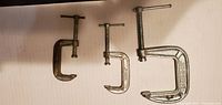 Photo shows 3 metal C-clamps of different sizes arranged on a flat surface for size comparison.