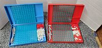 Open blue and red Battleship board game cases showing game boards, pegs, and ships inside.