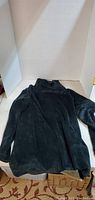 Dark blue velvety textured sweater laid flat showing full item front view and shape.
