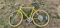 Side profile photo of vintage yellow Vista 10 speed bicycle showing frame, wheels, handlebars, saddle, derailleurs and pedals.