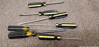 Photo showing the set of eight yellow and black handled screwdrivers with various shaft lengths and head types, laid out on carpet.