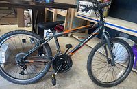 Side view showing the full frame and tires of the Huffy Granite mountain bike with orange and black decal.