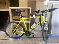 Full side view of yellow Giant bicycle showing frame, wheels, seat, handlebars, child's seat at rear, and water bottle on frame.