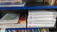 Shelf view showing slip-cased volumes 1–5, spiral-bound manual, and At Home book.