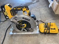 DeWalt circular saw with attached 20V XR battery and accompanying battery charger placed on a concrete surface