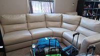 Full view of beige six piece leather sectional sofa with recliner seats in a room.