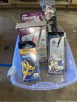 Four Estes model rocket kits and launch set in plastic storage tote on concrete floor