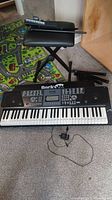 Photo showing Rock Jam RJ-561 keyboard, stool, and power adapter on carpeted floor.