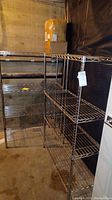 Full view of two metal wire shelving units standing side by side on concrete floor in storage basement area.