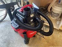 Front view of Craftsman wet/dry vacuum with attached hose and crevice nozzle.