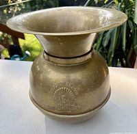 Front view of antique brass spittoon showing overall shape and patina