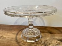 Side view of the clear pressed glass cake stand showing detailed stem and base patterns