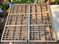 Overhead view of two side-by-side antique wood letterpress trays showing internal compartments and wood finish.