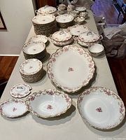 Overview of full set laid out on table showing plates, bowls, tureens, cups and platter