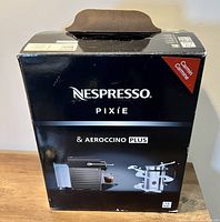 Box showing Nespresso Pixie and Aeroccino Plus branding, carmine color indicated.