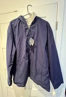 Navy blue side of the reversible men's Polo Ralph Lauren fall jacket on a hanger showing front view with zippered pockets and hood.