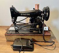 Front view of Singer sewing machine on original brown case with foot pedal and power cord laid out