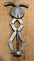 Front view of the vintage corkscrew wine opener showing the bug-like design on the top, metal arms and worm corkscrew below.