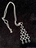 Full necklace displayed on black background showing the pendant with multi-diamond shape design and silver chain.