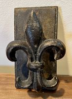 Front view of the vintage cast iron fleur de lys door knocker showing the entire fleur de lys on the rectangular backing plate.