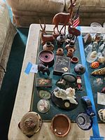 Photo showing full tabletop with carved wooden deer statues, ceramic vases and various figurines and decor pieces