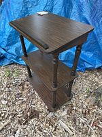 Front angled view of mid century wooden bible stand with three shelves and casters, showing the tilted top designed to hold a bible.