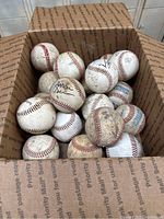 Box showing all 16 old baseballs with some signatures visible
