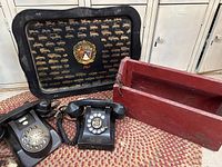 Photo showing the two black rotary phones, red wooden toolbox, and black metal Ford tray with 1961 logo.