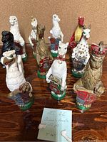 Group of 10 chalkware Queen’s Beasts figurines, arranged on a wooden surface with a note identifying them.