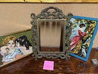 Photo showing large ornate Victorian-style frame with two needlepoint artworks on either side