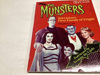 Photo of The Munsters 1989 hardcover book featuring main characters on the cover in color, title, author, and foreword credit visible.