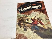 Cover of Lone Ranger comic book showing lone ranger in a red shirt and mask in a boat on rough water rapids.