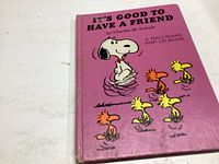 Photo of the pink hardcover pop-up book 'It's Good to Have a Friend' with Snoopy and Woodstocks on cover