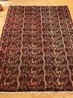 Full view of carpet laid flat showing floral patterned design with dominant dark cherry background and cream details.