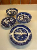 Set of 11 blue and white ironstone dishes laid out showing fruit nappies, cereal bowls, and bread and butter plates