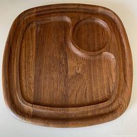 Top-down view of the entire square hardwood cheeseboard showing the three indented serving sections and natural wood grain.