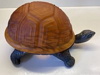 Full view of the amber textured glass tortoise lamp with metal base, showing the tortoise shape and amber glass shell.