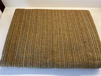 Folded upholstery fabric showing earth tone stripe pattern and texture.