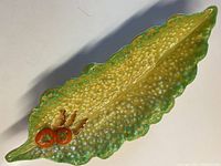 Top view of the elongated serving bowl showing mustard texture, green scalloped edges, and tomato decoration at the narrow end.