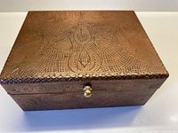 Front angled view of the rectangular box showing copper etching and brass knob.