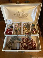 Vintage ivory jewellery box open showing satin-lined lid and multiple compartments with assorted costume jewellery and sterling pieces inside