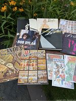 Photo showing a spread of various books and comic books with colorful covers including art painting lessons, Bob Dylan, Barbie, X-Men, and more.
