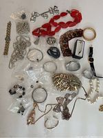 Overview of all jewelry items including bracelets, necklaces, a watch, and earrings laid out on a white surface.
