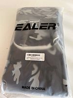 Front view of the Ealer bag inside clear plastic packaging showing the logo and camo pattern.