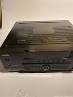 Top and front view of KLH R5100 stereo receiver showing front display, control buttons, and ventilation slots on top.