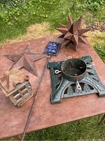 Overview photo showing all metal lawn ornaments and Christmas tree stand on a wooden table outdoors.
