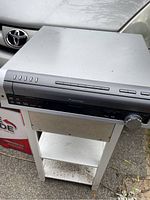 Pioneer DVD/CD/MP3 player with amplifier shown on a small table, silver in color with front panel buttons and volume knob.