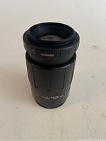 Top view of Tamron camera lens showing the front glass element and Tamron branding on the barrel.